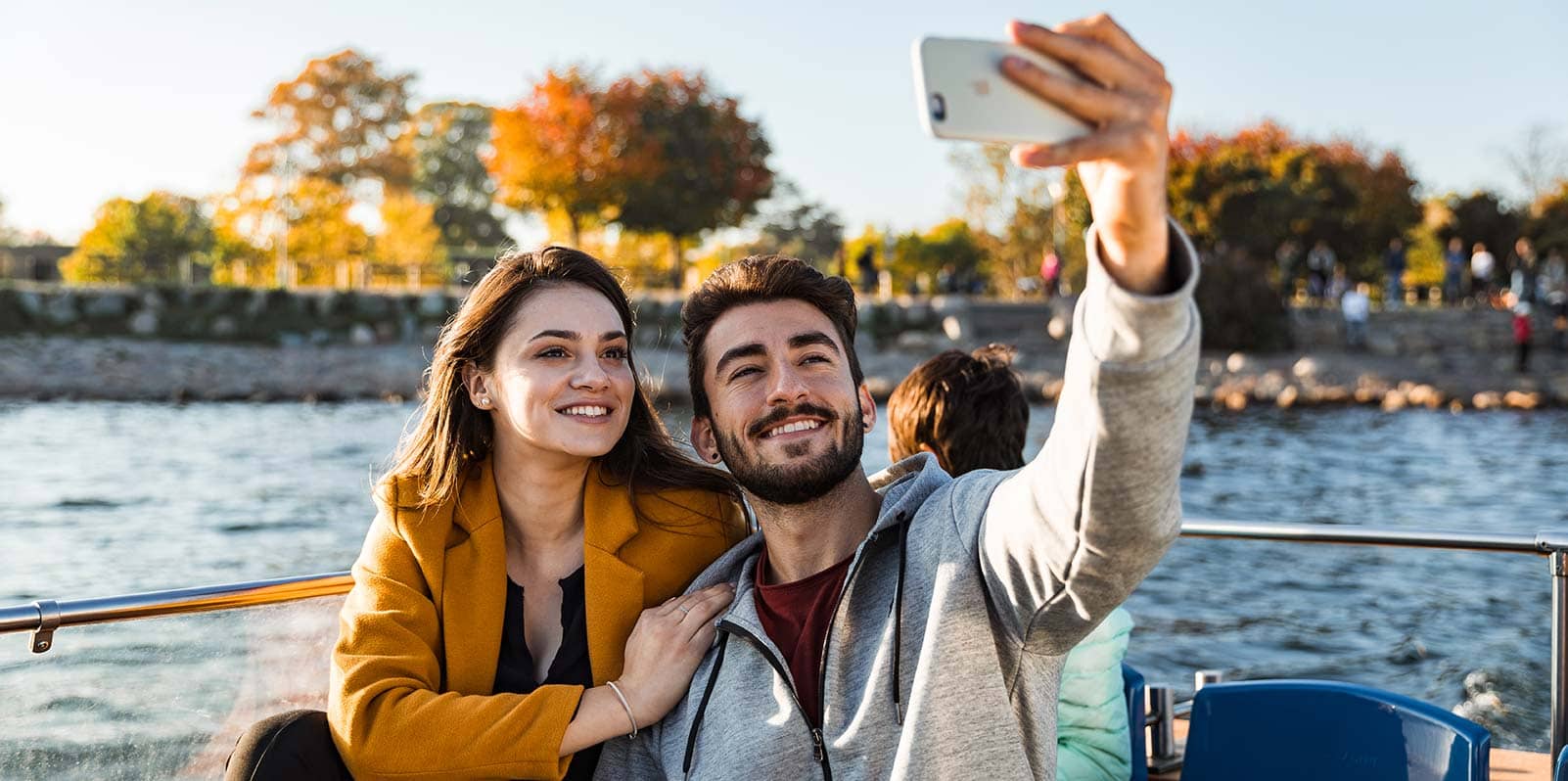 Man and a woman taking a selfie on the HOHO boat in Copenhagen with the water and trees on the background